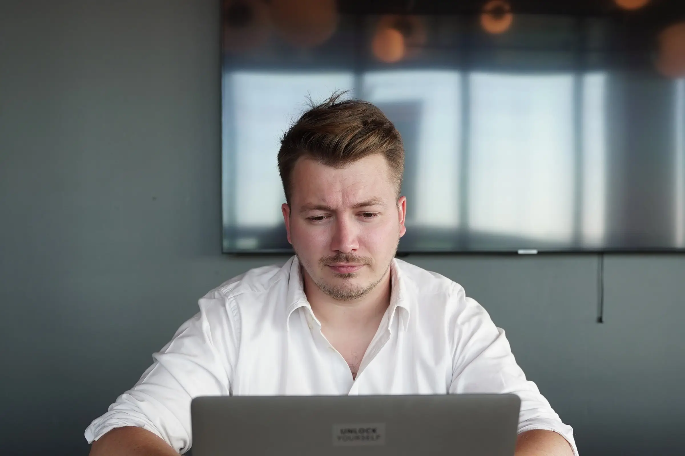 Alexandre Bury, fondateur d'Expans Digital, concentré devant son ordinateur portable, un écran mural derrière lui.